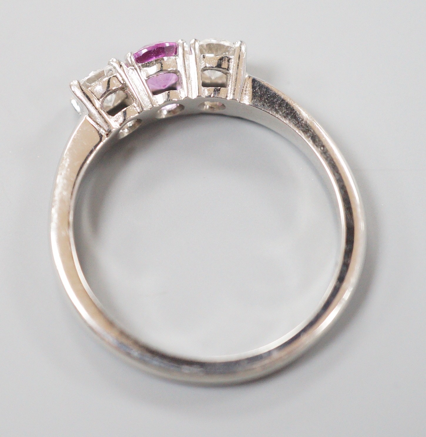 A modern platinum, pink sapphire and two stone round cut diamond set ring, size O, gross weight 5.4 grams